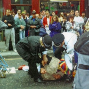 Photo: protester on the ground being arrested at DAN's disabled people's parking protest, Dale Street Liverpool, 1994